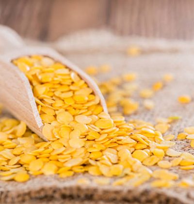 Yellow Lentils (detailed close-up shot) on wooden background